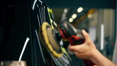 Benzin istasyonunu temizleyen arabayı kapat. Siyah bir araba sarı bantla kaplıdır. Özel bir hortumla araba cilalama işlemi.