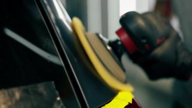 Benzin istasyonunu temizleyen arabayı kapat. Siyah bir araba sarı bantla kaplıdır. Özel bir hortumla araba cilalama işlemi.