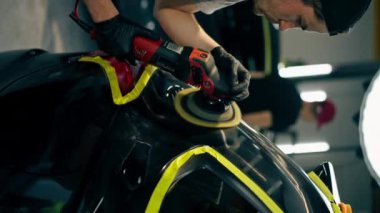 Bir benzin istasyonunda ayrıntılı olarak çekilen dikey video, siyah bir araba sarı bantla kaplıdır. Özel bir hortumla araba cilalama işlemi.