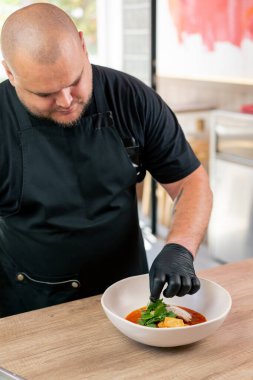 Bir fast food işletmesinde siyah üniformalı büyük bir şef Japon udon çorbasını hazırlar.