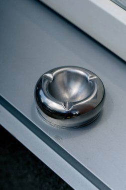 Sokakta, çöp tenekesinin metal yüzeyindeki bir restorana yakın bir yerde sigara izmaritleri için metal bir kül tablası var.