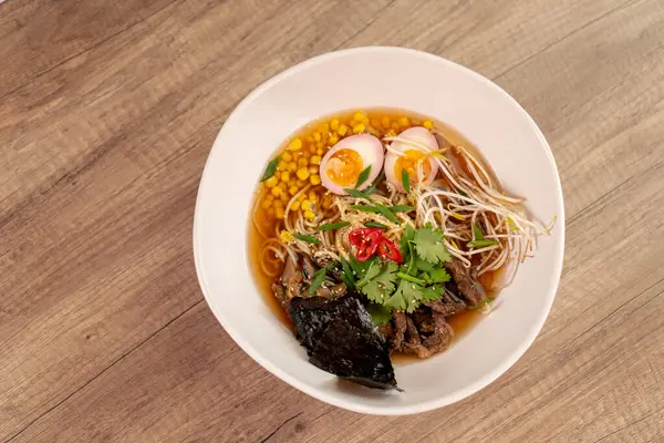 Bir restoranda, açık bir masada, Japon udon çorbası, yumurta ve erişte karışımı Japon hafif çorbası ile yakın çekim.