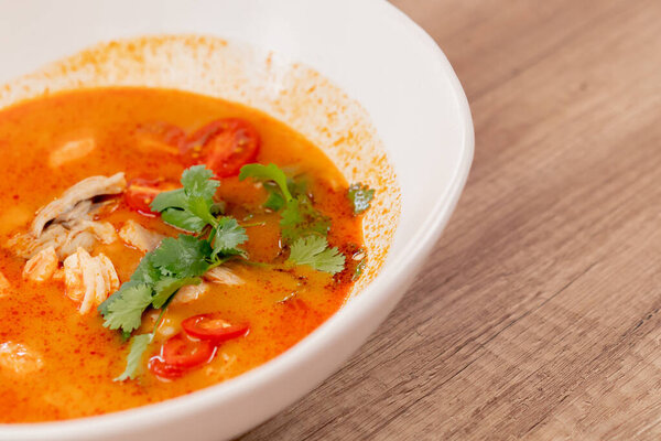 закрывается в ресторане на светлом столе белая тарелка с японским удонским супом с красным супом с креветками и рисовым японским легким супом