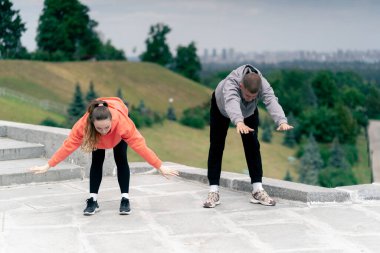 Parkta birbirine aşık genç bir çift spor yapıyor. Sağlıklı yaşam tarzı senkronize hareketleri ısıtıyor.