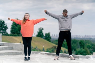 Parkta birbirine aşık genç bir çift spor yapıyor. Sağlıklı yaşam tarzı senkronize hareketleri ısıtıyor.