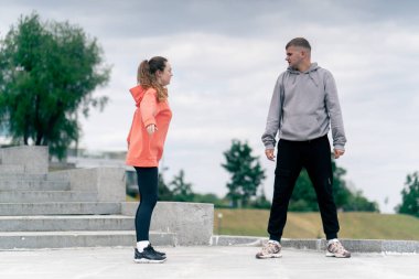 Parkta birbirine aşık genç bir çift spor yapıyor. Sağlıklı yaşam tarzı senkronize hareketleri ısıtıyor.