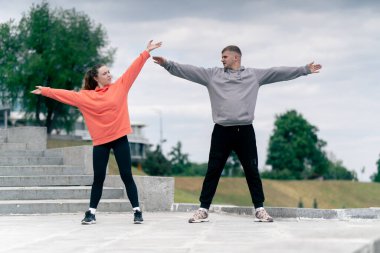 Parkta birbirine aşık genç bir çift spor yapıyor. Sağlıklı yaşam tarzı senkronize hareketleri ısıtıyor.