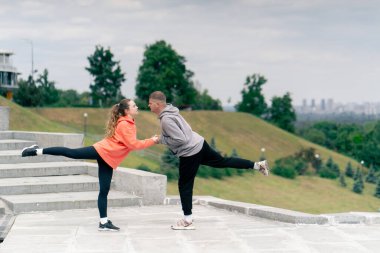 Parkta birbirine aşık genç bir çift spor yapıyor. Sağlıklı yaşam tarzı senkronize hareketleri ısıtıyor.