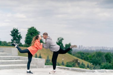 Parkta birbirine aşık genç bir çift spor yapıyor. Sağlıklı yaşam tarzı senkronize hareketleri ısıtıyor.