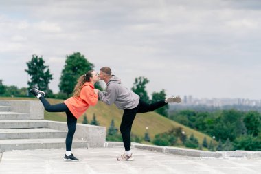 Parkta birbirine aşık genç bir çift spor yapıyor. Sağlıklı yaşam tarzı senkronize hareketleri ısıtıyor.