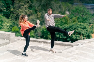 Parkta birbirine aşık genç bir çift spor yapıyor. Sağlıklı yaşam tarzı senkronize hareketleri ısıtıyor.