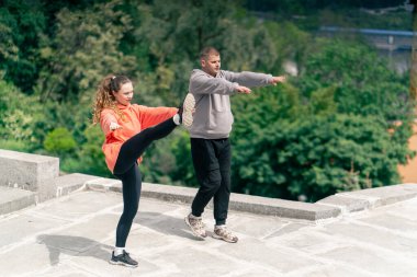 Parkta birbirine aşık genç bir çift spor yapıyor. Sağlıklı yaşam tarzı senkronize hareketleri ısıtıyor.
