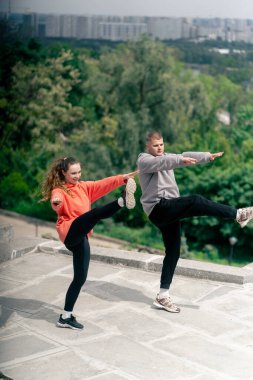 Parkta birbirine aşık genç bir çift spor yapıyor. Sağlıklı yaşam tarzı senkronize hareketleri ısıtıyor.