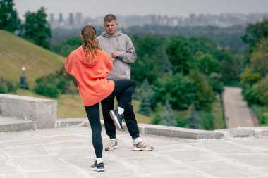 Parkta birbirine aşık genç bir çift spor yapıyor. Sağlıklı yaşam tarzı senkronize hareketleri ısıtıyor.