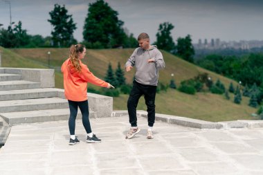 Parkta birbirine aşık genç bir çift spor yapıyor. Sağlıklı yaşam tarzı senkronize hareketleri ısıtıyor.