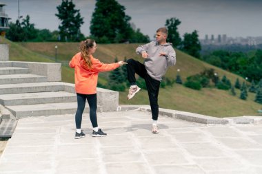 Parkta birbirine aşık genç bir çift spor yapıyor. Sağlıklı yaşam tarzı senkronize hareketleri ısıtıyor.