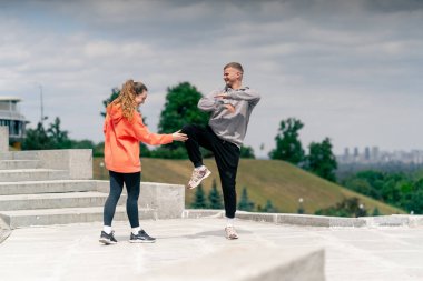 Parkta birbirine aşık genç bir çift spor yapıyor. Sağlıklı yaşam tarzı senkronize hareketleri ısıtıyor.