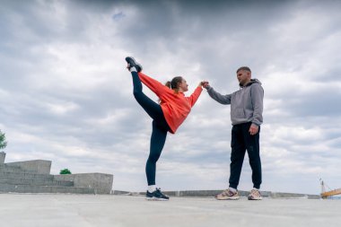 Parkta birbirine aşık genç bir çift spor yapıyor. Sağlıklı yaşam tarzı senkronize hareketleri ısıtıyor.