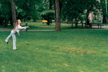 Doğadaki parkta genç bir çift çocukluktaki aktif aile haftasonuna frizbi oynuyor.