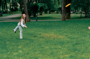 Doğadaki parkta genç bir çift çocukluktaki aktif aile haftasonuna frizbi oynuyor.