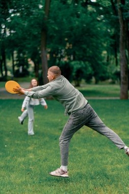 Doğadaki parkta genç bir çift çocukluktaki aktif aile haftasonuna frizbi oynuyor.