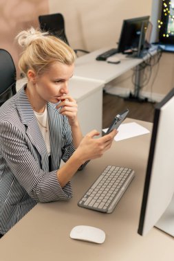 Aydınlık bir ofiste sarışın genç bir çalışan beyaz ekranda çalışıyor. Masanın üstünde. Modern ofis ışınları, iş yerinde bir duraksama projesi üzerinde çalışıyor.