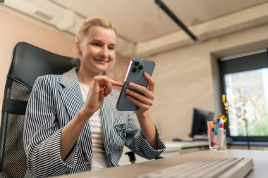 Aydınlık bir ofiste sarışın genç bir çalışan beyaz ekranda çalışıyor. Masanın üstünde. Modern ofis ışınları, iş yerinde bir duraksama projesi üzerinde çalışıyor.