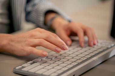 Beyaz bir klavye ofis cihazına yazı yazan genç kadınların yakın çekimi. Çıplak manikür profesyonel klavye.