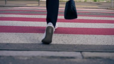 Kırmızı ve beyaz şeritleri geçen yayalar üzerinde beyaz güzellikteki bacakları yakın çekimde yol boyunca güvenli bir şekilde ilerliyorlar.