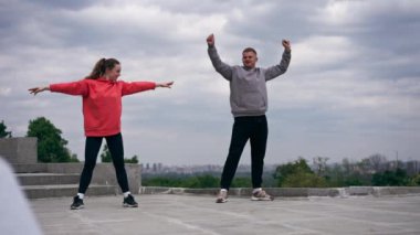 Parkta birbirine aşık genç bir çift spor yapıyor. Sağlıklı yaşam tarzı senkronize hareketleri ısıtıyor.