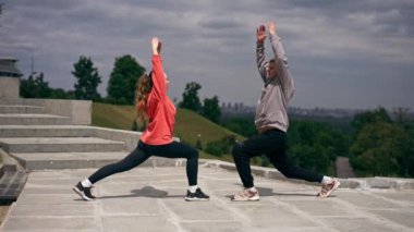 Parkta birbirine aşık genç bir çift spor yapıyor. Sağlıklı yaşam tarzı senkronize hareketleri ısıtıyor.