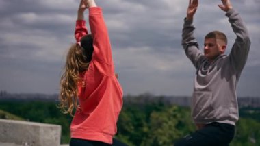 Parkta birbirine aşık genç bir çift spor yapıyor. Sağlıklı yaşam tarzı senkronize hareketleri ısıtıyor.