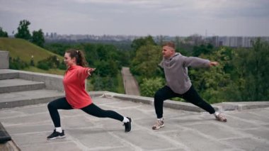 Parkta birbirine aşık genç bir çift spor yapıyor. Sağlıklı yaşam tarzı senkronize hareketleri ısıtıyor.
