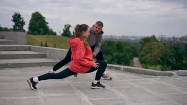 Parkta birbirine aşık genç bir çift spor yapıyor. Sağlıklı yaşam tarzı senkronize hareketleri ısıtıyor.