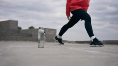 Parkta turuncu kapüşonlu genç bir kız ısınıyor sağlıklı bir yaşam tarzı meditasyon yapıyor bulutlu bir havada duruyor.