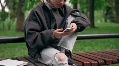 Parkta siyah ceketli, saçları yerden kesilmiş, cep telefonuyla mesajlaşan yalnız bir kız vardı.