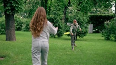 Doğadaki parkta genç bir çift çocukluktaki aktif aile haftasonuna frizbi oynuyor.