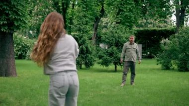 Doğadaki parkta genç bir çift çocukluktaki aktif aile haftasonuna frizbi oynuyor.
