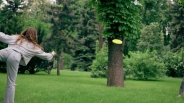 Doğadaki parkta genç bir çift çocukluktaki aktif aile haftasonuna frizbi oynuyor.