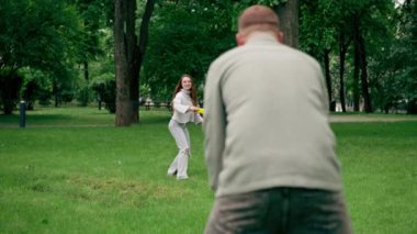 Doğadaki parkta genç bir çift çocukluktaki aktif aile haftasonuna frizbi oynuyor.