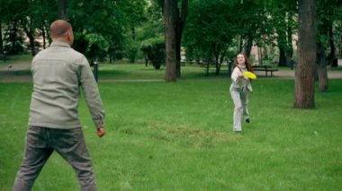 Doğadaki parkta genç bir çift çocukluktaki aktif aile haftasonuna frizbi oynuyor.