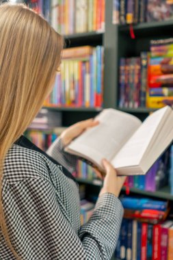 Bir kitapçıya yakın çekimde genç bir kız sınav öğrenci yaşam tarzına hazırlanmak için kendine yeni bir kitap seçer.