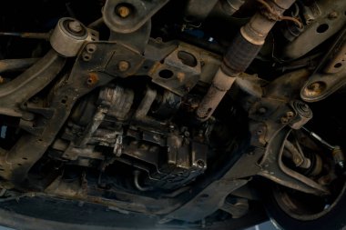 Bir araba servisinde asansörle yakın plan. Tekerlekle ilgili bir sorunu tamir etmek için bir makine. Paslı yayı olan bir tekerlek.