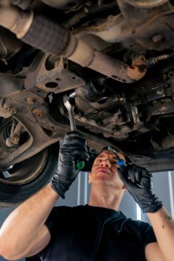 Bir benzin istasyonundaki oto tamirciyi kapat asansörde kaldırılan bir arabayı kontrol et, mekanik bir araçla arızaları düzelt motor alt gövdenin parçasını