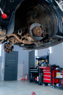 Bir otomobil tamircisi için özel bir mekanizma tarafından bir benzin istasyonunda tekersiz siyah bir arabanın yakın plan çekimi.