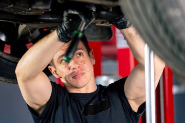 Bir benzin istasyonundaki oto tamirciyi kapat asansörde kaldırılan bir arabayı kontrol et, mekanik bir araçla arızaları düzelt motor alt gövdenin parçasını