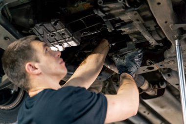 Bir benzin istasyonundaki oto tamirciyi kapat asansörde kaldırılan bir arabayı kontrol et, mekanik bir araçla arızaları düzelt motor alt gövdenin parçasını