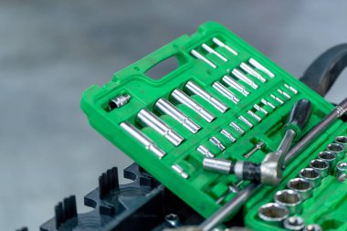 Bir araba servisinde, yeşil bir el çantasının içinde cıvata soketi başlığı için anahtarlar var.