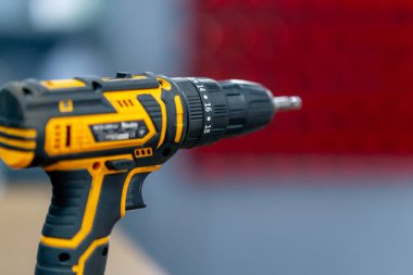 Bulanık kırmızı arkaplanda bir araba servisine yakın plan, kafanın hız dönüşünü ayarlayan siyah ve sarı bir tornavida