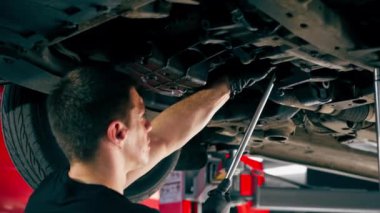 Bir benzin istasyonundaki oto tamirciyi kapat asansörde kaldırılan bir arabayı kontrol et, mekanik bir araçla arızaları düzelt motor alt gövdenin parçasını